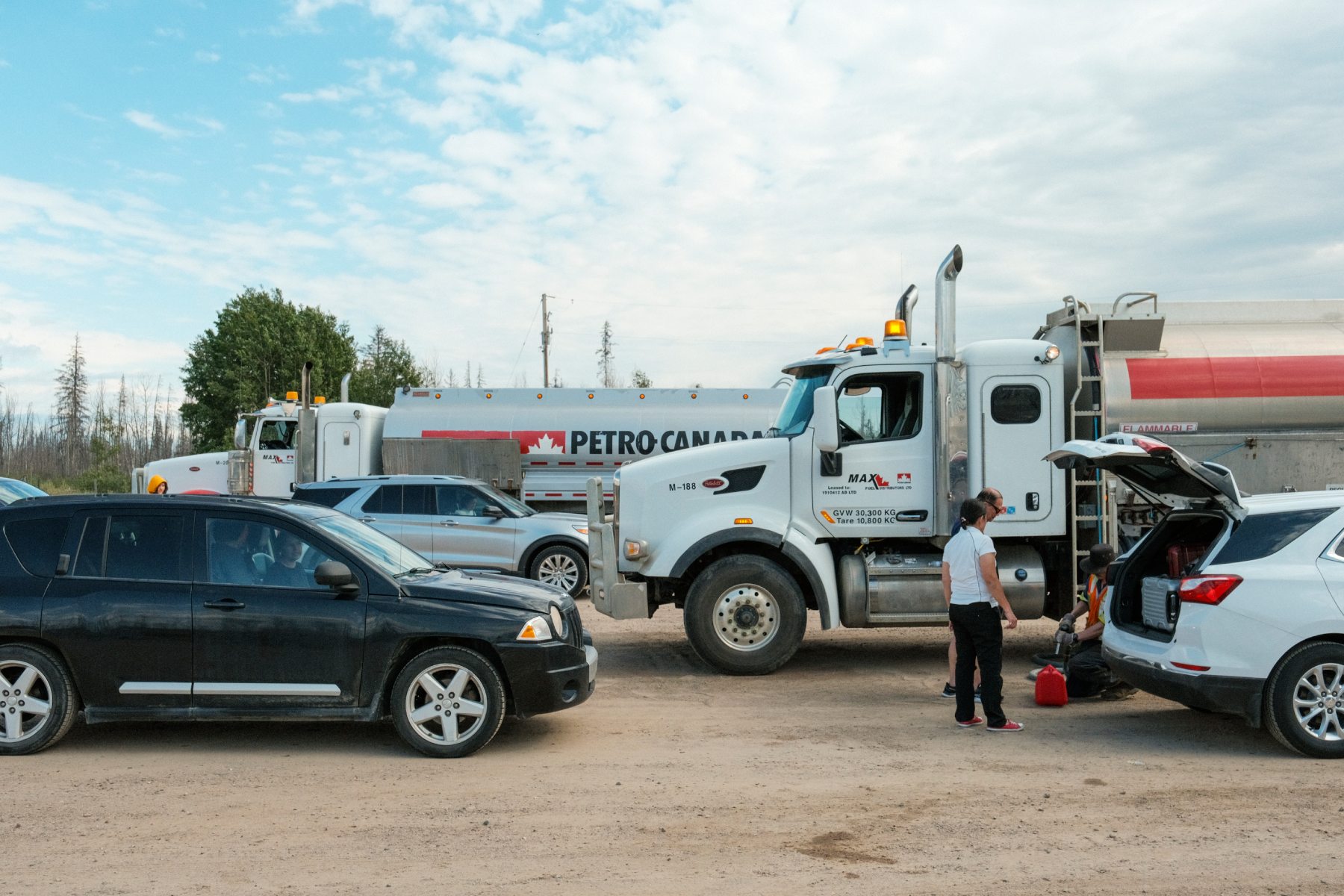 A photo of gas trucks and regular vehicles under a blue sky.