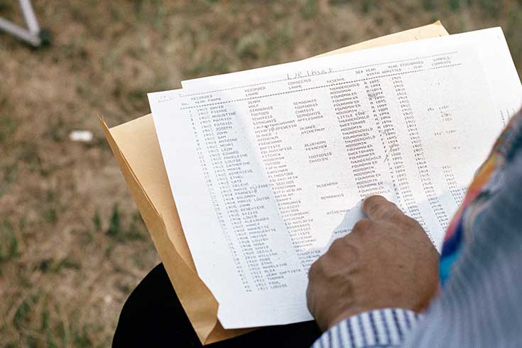 An Indigenous person looking at a list of names.