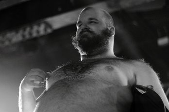 Shirtless, bearded man in front of stage lights