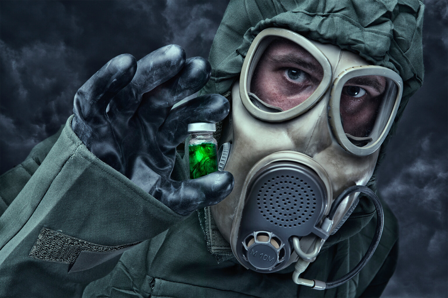 A photo shows a man in a hazmat suit holding a vial containing a green liquid