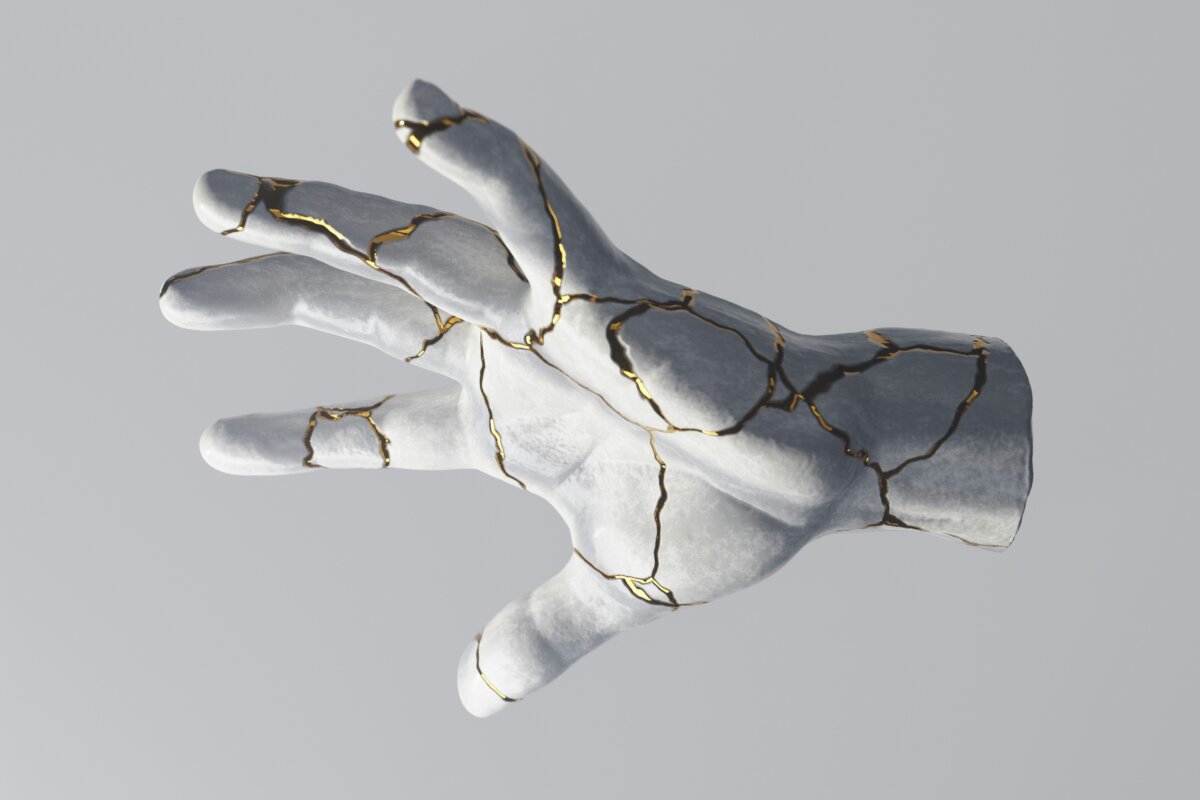 Greyscale hand reaching out with cracks filled with gold.